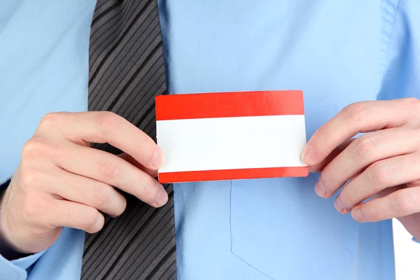 Empresario vistiendo camisa azul con corbata y sosteniendo la etiqueta de nombre en blanco de cerca — Foto de Stock