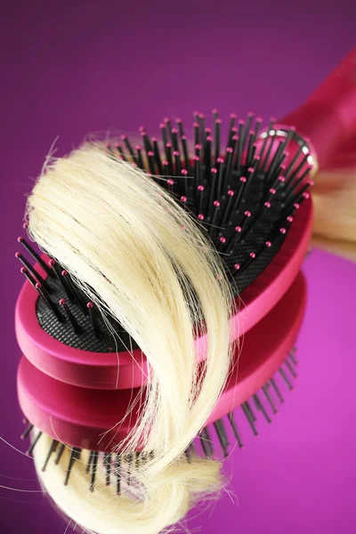 Comb brush with hair on purple background — Stock Photo, Image