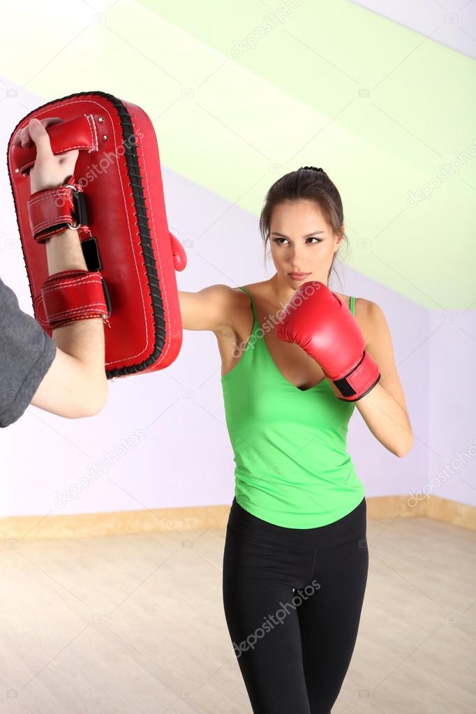 Young beautiful woman with boxing gloves at workout, at gym
