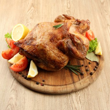 ahşap masa üzerinde plaka üzerinde sebze ile bütün kavrulmuş tavuk