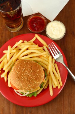 patates kızartması ve ahşap zemin üzerinde soğuk içecek ile lezzetli peynirli burger