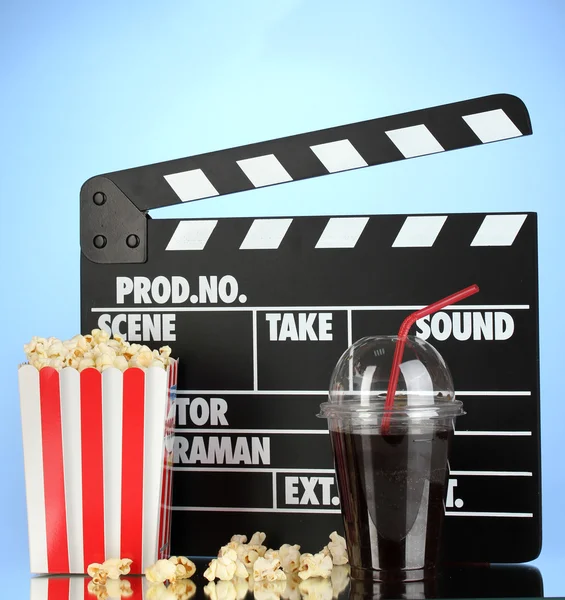 Film clapperboard, cola et pop-corn sur fond bleu — Photo