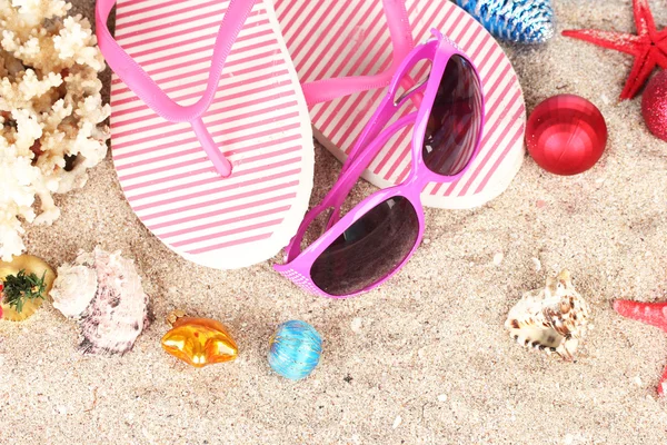 Bolas de Natal, conchas e acessórios de praia na areia, close-up — Fotografia de Stock