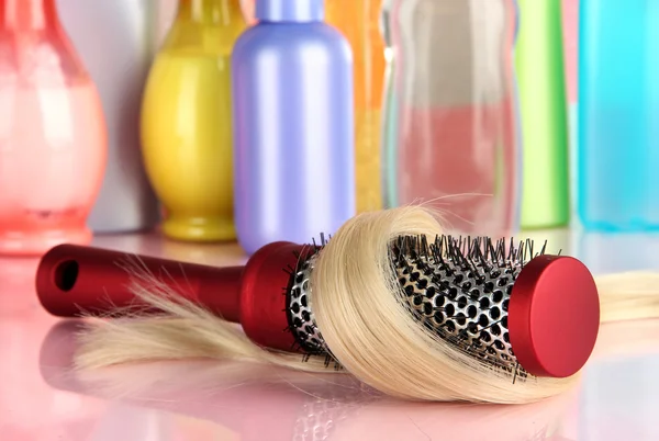 Escova de pente com cabelo e garrafas de cosméticos no banheiro — Fotografia de Stock