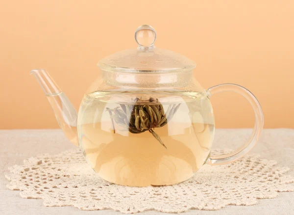 Экзотический зеленый чай с цветами в стеклянной чашке на столе на цветном фоне. — стоковое фото