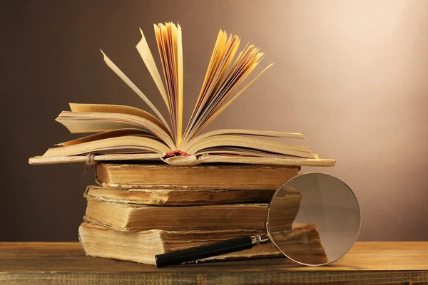 Magnifying glass and books on table — Stock Photo, Image