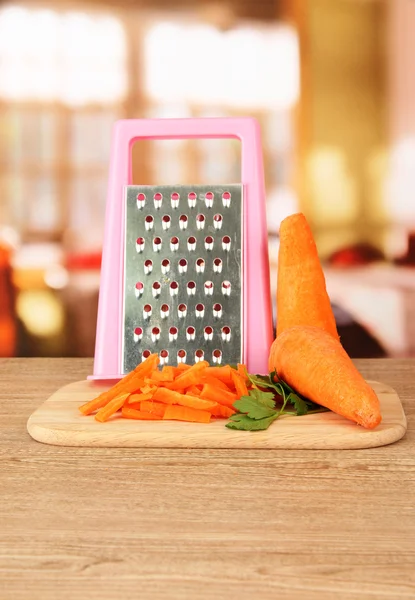 Zanahorias con rallador en la tabla de cortar en la mesa en la cocina — Foto de Stock