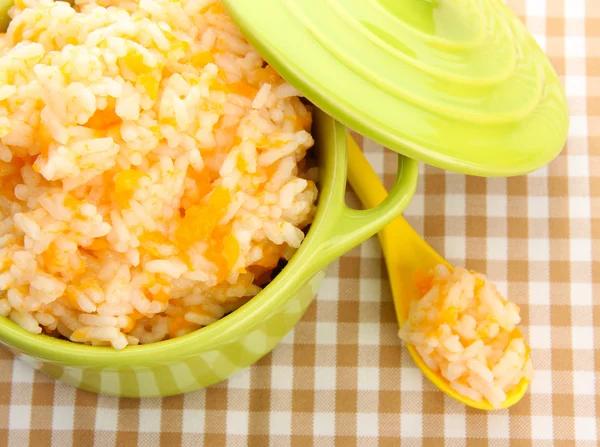 Taste rice porridge with pumpkin in saucepan on tablecloth background — Stock Photo, Image