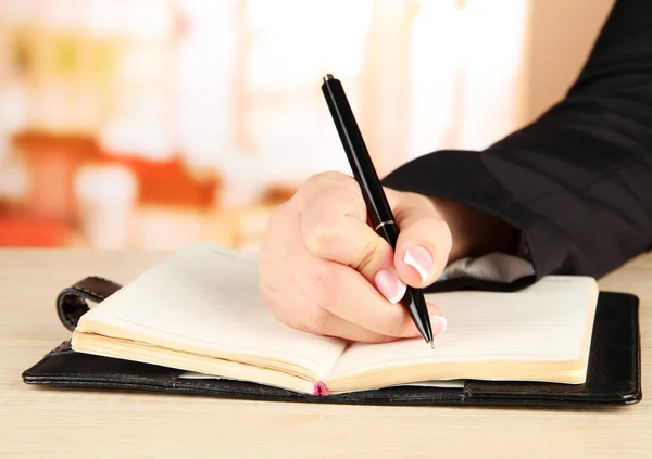 Mão escreva no caderno, no fundo brilhante — Fotografia de Stock