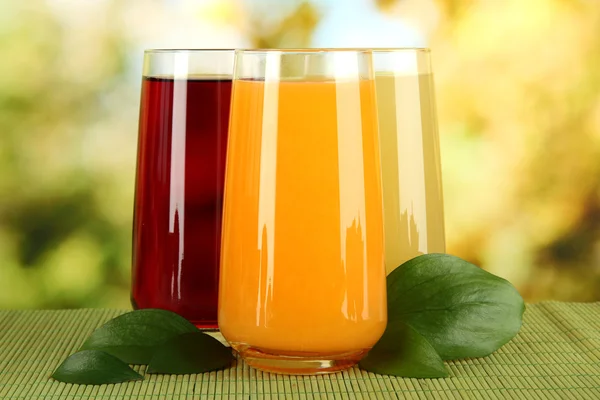 Glasses of juise and leafs on table on bright background — Stock Photo, Image
