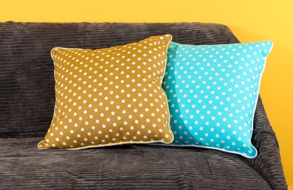 Colorful pillows on couch on yellow background — Stock Photo, Image