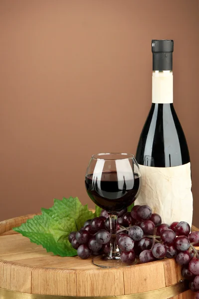 Skład butelek wina, szkło i moszczu winogronowego, na drewnianej beczce, na brązowym tle — Zdjęcie stockowe