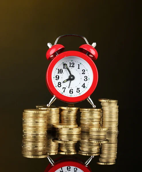 Alarm clock with coins on dark background — Stock Photo, Image