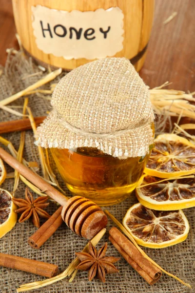 Jar of honey, wooden barrel, drizzler and dried lemons on wooden background — Stock Photo, Image