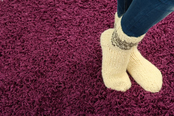 Patas femeninas en calcetines de colores sobre fondo de alfombra de color —  Fotos de Stock