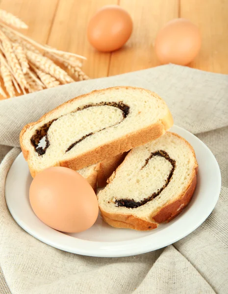 Pane con semi di papavero su piatto di colore, su sfondo di legno — Foto Stock