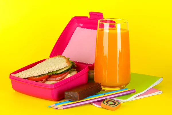 与三文治、 果汁和文具在黄色背景上的午餐盒 — 图库照片