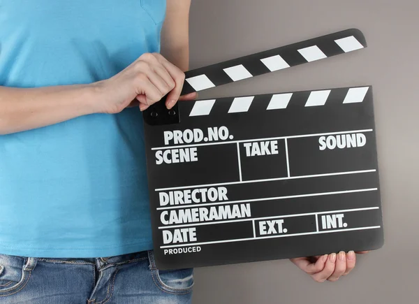 Movie production clapper board in hands on grey background — Stock Photo, Image