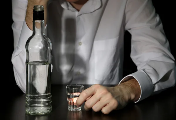 Человек с бутылкой алкоголя, на черном фоне — стоковое фото