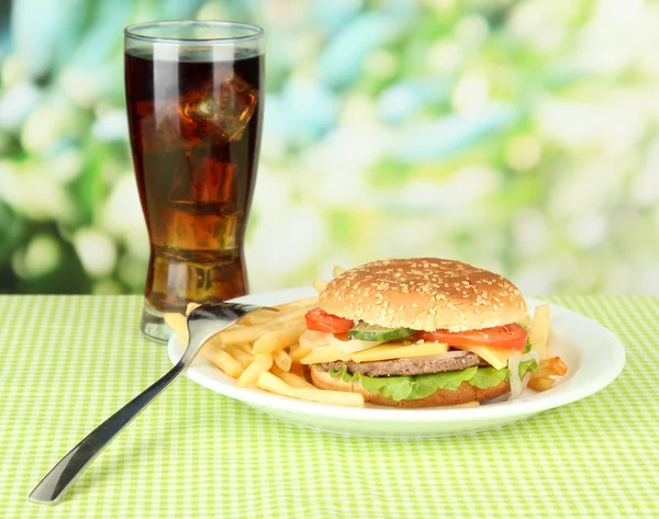 Tasty cheeseburger with fried potatoes and cold drink, on bright background — Stock Photo, Image