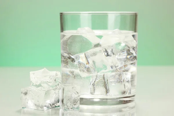 Ice cubes in glass on light green background — Stock Photo, Image