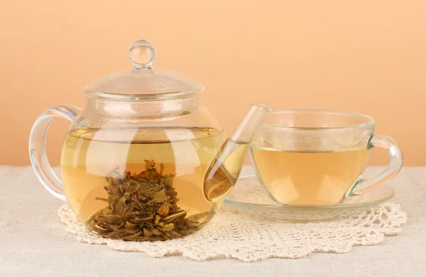 Exotic green tea with flowers in glass teapot on table on color background — Stock Photo, Image