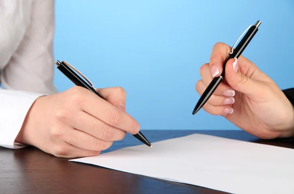 Deux partenaires commerciaux signant le document, sur fond bleu — Photo