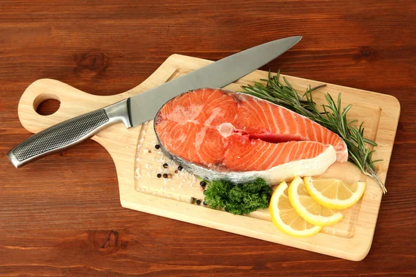 Fresh salmon steak on cutting board, on wooden background — Stock Photo, Image