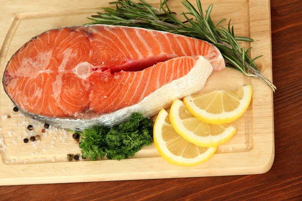 Fresh salmon steak on cutting board, on wooden background — Stock Photo, Image