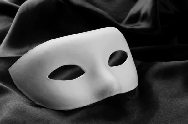 White mask, on black silk fabric — Stock Photo, Image