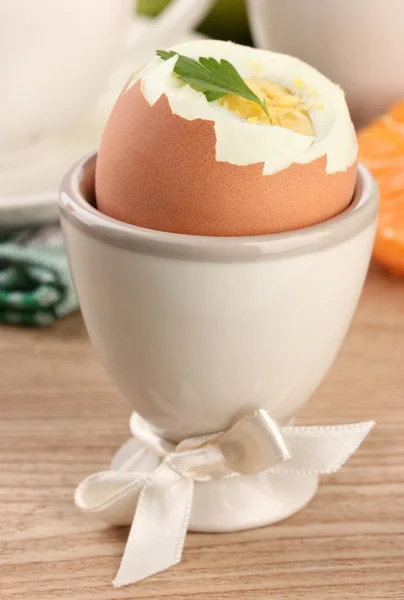 Gekookt ei in egg cup, op houten tafel — Stockfoto