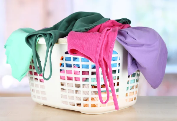 Clothes in plastic basket on table in room — Stock Photo, Image