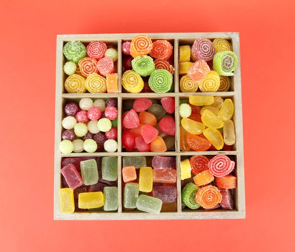 Multicolor candies in wooden box, on color background — Stock Photo, Image