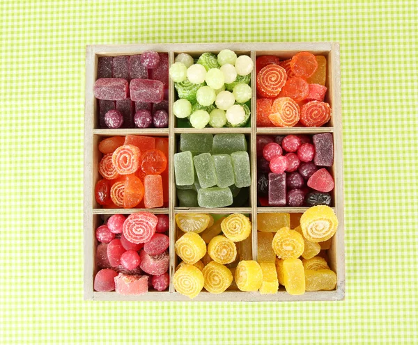Ahşap kutusunda, renkli arka plan üzerinde renkli şekerler — Stok fotoğraf