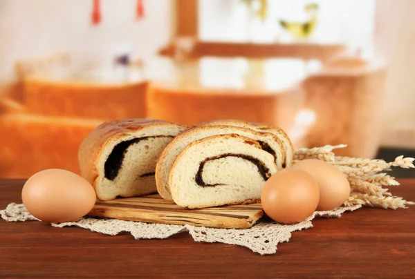 Pan con semillas de amapola en la tabla de cortar, sobre un fondo brillante —  Fotos de Stock