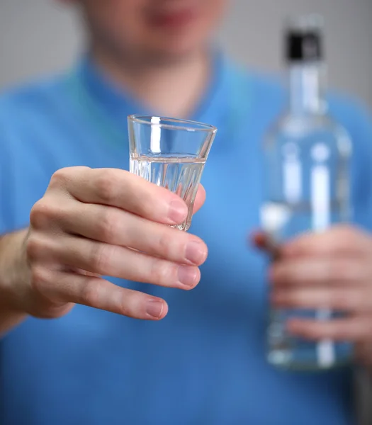 Homme avec verre d'alcool, sur fond gris — Photo