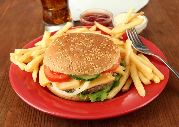 Sabrosa hamburguesa con patatas fritas y bebida fría, sobre fondo de madera —  Fotos de Stock