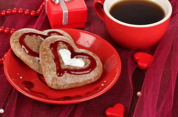 Biscoitos de chocolate em forma de coração com xícara de café na toalha de mesa rosa close-up — Fotografia de Stock