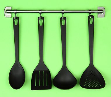 Gümüş kanca, yeşil arka plan üzerinde siyah mutfak gereçleri