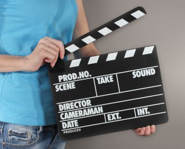 Film üretim clapper panosundaki gri arka plan üzerinde eller