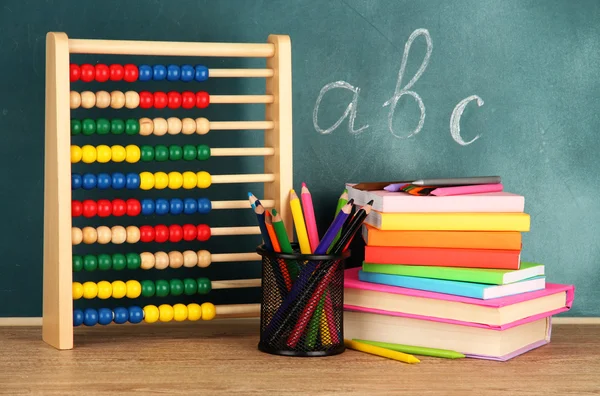 Toy abacus, books and pencils on table, on school desk background — Stock Photo, Image