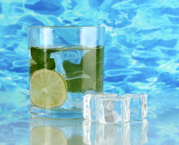 Glass of water with ice, mint and lime on sea background — Stock Photo, Image