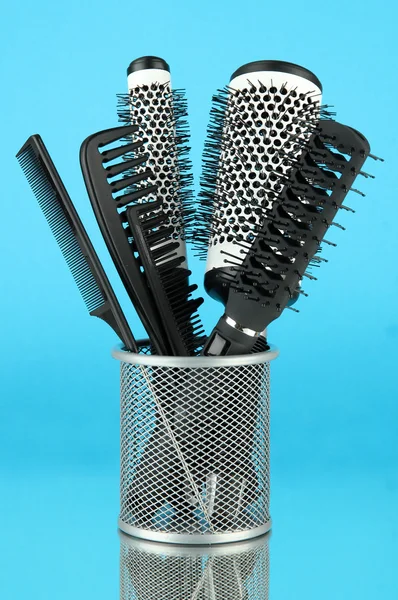 Cesta de hierro con peines y cepillos redondos, sobre fondo de color — Foto de Stock