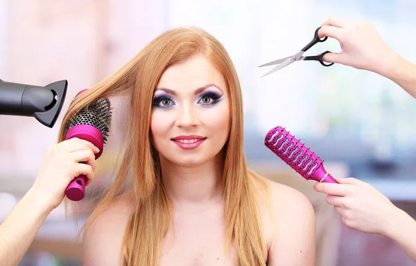 Beautiful woman and hands with brushes, scissors and hairdryer in beauty salon — Stock Photo, Image