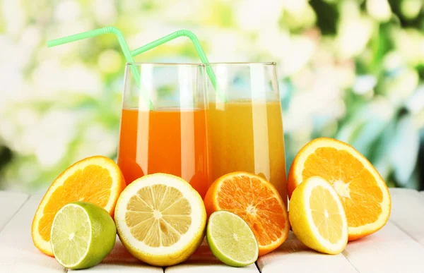 Lots ripe citrus with juices on wooden table on natural background — Stock Photo, Image