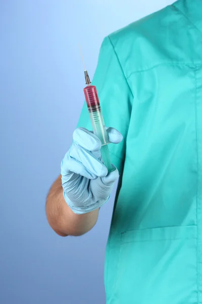 Doktor s injekční stříkačkou na modrém pozadí — Stock fotografie