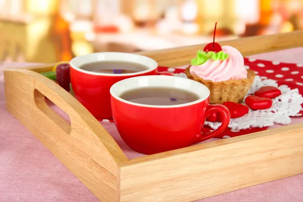 Cups of tea with cake on wooden tray on table in cafe — Stock Photo, Image