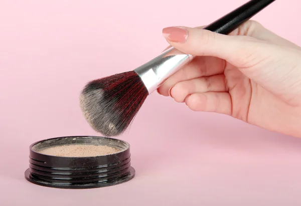 Powder and brush in hand on pink background — Stok Foto