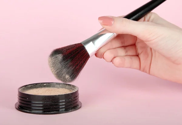 Powder and brush in hand on pink background — Stock Photo, Image