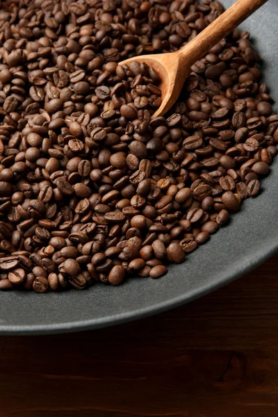 Black wok pan with coffee beans on wooden table, close up — Stock Photo, Image